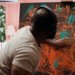 artist listening to music and creating an abstract painting with his fingers