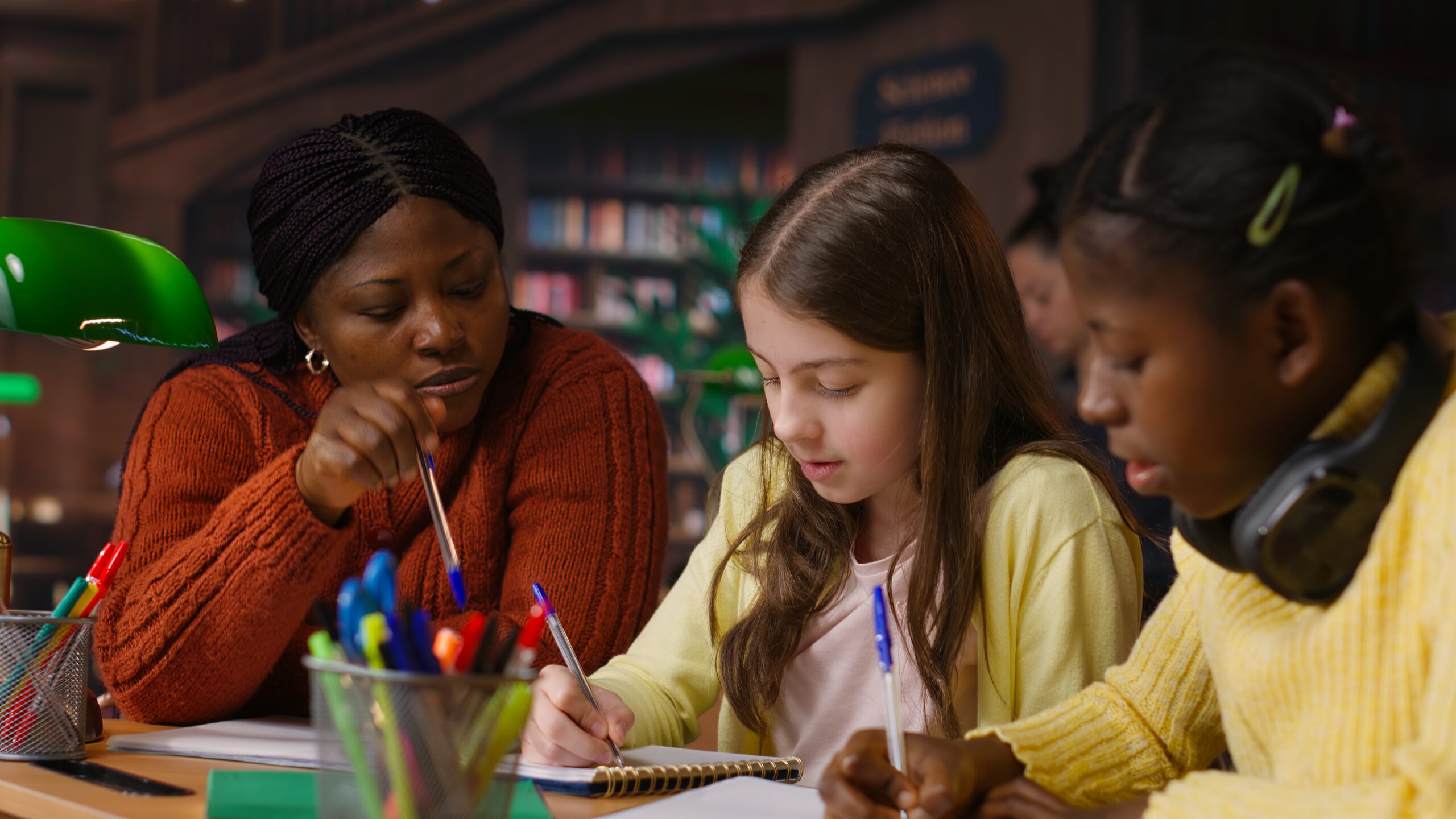 female teacher assisting pupils with class homework and mentoring